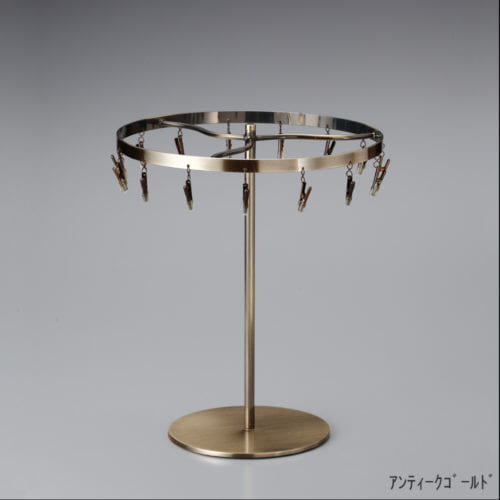 ●商品名:チーフ・ハンカチスタンド 回転式 ●表面処理:アンティークゴールドメッキ(AG)仕上 ●寸法:高さ300mm 上部回転リング直径240mm ●上部回転式リング:クリップ15個付 ●材質:スチール ●特長:百貨店様では棚板高さのスパンが30cm強の設定が多いと教えてもらい、では「高さ30cmのスペースにフィットするチーフツリーを作ろう」ということで高さ30cmのチーフツリーを製造しました。また、クリップの先端には塩ビのキャップを装着し、展示商品を傷つけにくい仕上がりになっています。 ●生産国:日本(タヤ自社工場)