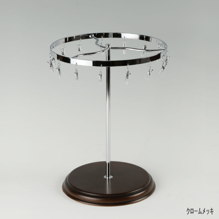 ●商品名:チーフ・ハンカチスタンド回転式 木製ベース仕様
●表面処理:クロームメッキ(Cr)仕上
●寸法:高さ315mm 上部回転リング直径240mm
●上部回転式リング:クリップ15個付
●材質:スチール
●特長:百貨店様では棚板高さのスパンが30cm強の設定が多いと教えてもらい、では「高さ30cmのスペースにフィットするチーフツリーを作ろう」ということで高さ30cmのチーフツリーを製造しました。また、クリップの先端には塩ビのキャップを装着し、展示商品を傷つけにくい仕上がりになっています。さらに、木製のベースを組み合わせることで、落ち着きのある存在感と高級感を演出できます。
●生産国:日本(タヤ自社工場)