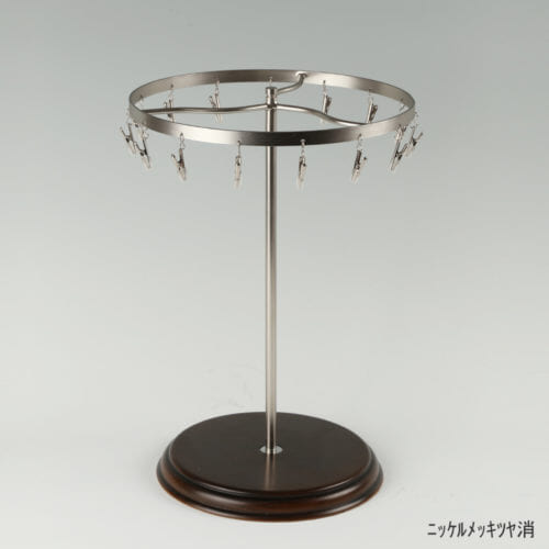 ●商品名:チーフ・ハンカチスタンド回転式 木製ベース仕様 ●表面処理:ニッケルツヤ消(NI-M)仕上 ●寸法:高さ315mm 上部回転リング直径240mm ●上部回転式リング:クリップ15個付 ●材質:スチール ●特長:百貨店様では棚板高さのスパンが30cm強の設定が多いと教えてもらい、では「高さ30cmのスペースにフィットするチーフツリーを作ろう」ということで高さ30cmのチーフツリーを製造しました。また、クリップの先端には塩ビのキャップを装着し、展示商品を傷つけにくい仕上がりになっています。さらに、木製のベースを組み合わせることで、落ち着きのある存在感と高級感を演出できます。 ●生産国:日本(タヤ自社工場)