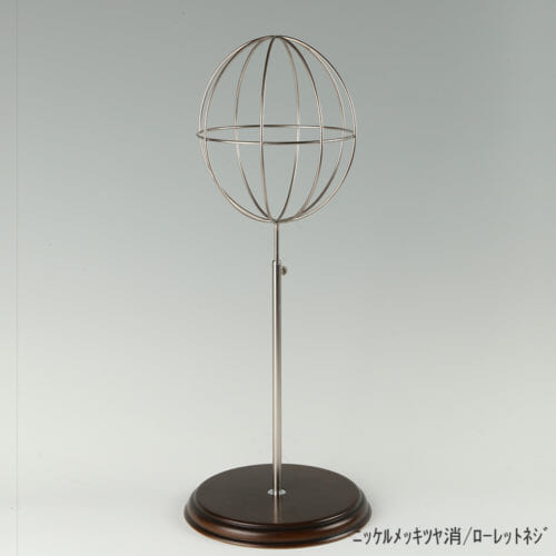 ●商品名:帽子スタンド 球体型-M ローレットネジ・木製ベース仕様 ●表面処理:ニッケルツヤ消(NI-M)仕上 ●寸法:高さ465~575mm ●ヘッド部:ワイヤー製ラグビーボール型球体ヘッド ●ヘッド:上下可動式(伸縮式) ●材質:スチール・木製(ベース) ●特長:抜け感がおしゃれなワイヤーヘッドに木製ベースを組み合わせ、落ち着きのある存在感と高級感を演出するツール ●生産国:日本(タヤ自社工場)