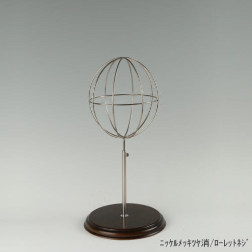 ●商品名:帽子スタンド 球体型-S ローレットネジ・木製ベース仕様 ●表面処理:ニッケルツヤ消(NI-M)仕上 ●寸法:高さ410~500mm ●ヘッド部:ワイヤー製ラグビーボール型球体ヘッド ●ヘッド:上下可動式(伸縮式) ●材質:スチール・木製(ベース) ●特長:抜け感がおしゃれなワイヤーヘッドに木製ベースを組み合わせ、落ち着きのある存在感と高級感を演出するツール ●生産国:日本(タヤ自社工場)