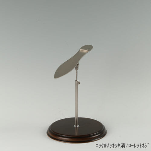 ●商品名:シューズスタンド片足用 ローレットネジ・木製ベース仕様 ●表面処理:ニッケルツヤ消(NI-M)仕上仕上 ●寸法:高さ高さ230~320mm ●ヘッド部:傾斜角度調整機能付。靴滑り落ち防止部材溶接留。 ●ヘッド:上下可動式(伸縮式) ●材質:スチール ●特長:展示物である靴のデザインを際立たせる天板デザイン設計。天板を足型状にすることにより、靴を乗せると天板が隠れるサイズで製造。天板が見えなくなる事によりお客様の視線が展示物の靴に集中、靴のデザインが際立ちます。 ●片足用スタンドである理由:両足分の靴をセットで展示しておくと、靴を持って行かれてしまう可能性が高くなるとのお話を聞き、通常品としては片足用のシューズスタンドをご用意しました。また、木製のベースを組み合わせることで、落ち着きのある存在感と高級感を演出できます。 ●生産国:日本(タヤ自社工場)