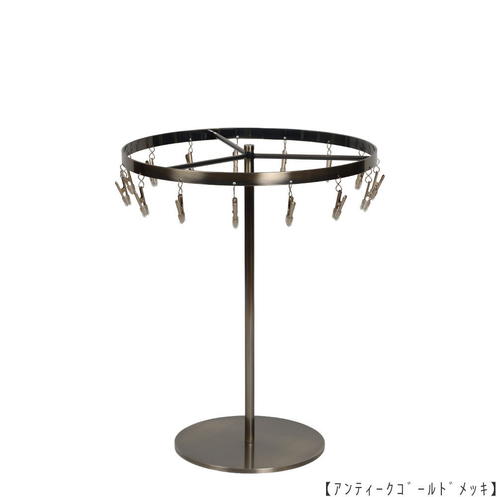 ●商品名:チーフ・ハンカチスタンド 回転式
●表面処理:アンティークゴールド(AG)仕上
●寸法:高さ300mm 上部回転リング直径240mm
●上部回転式リング:クリップ15個付
●材質:スチール
●特長:百貨店様では棚板高さのスパンが30cm強の設定が多いと教えてもらい、
では「高さ30cmのスペースにフィットするチーフツリーを作ろう」ということで高さ30cmのチーフツリーを製造しました。
また、クリップの先端には塩ビのキャップを装着し、展示商品を傷つけにくい仕上がりになっています。
●生産国:日本(タヤ自社工場)
※AGのみ先行リニューアル(別画像参照)